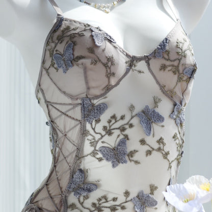 Sheer bodysuit with grey butterfly embroidery and floral lace detailing, featuring a lace-up side design on transparent mesh fabric, displayed on a mannequin.
