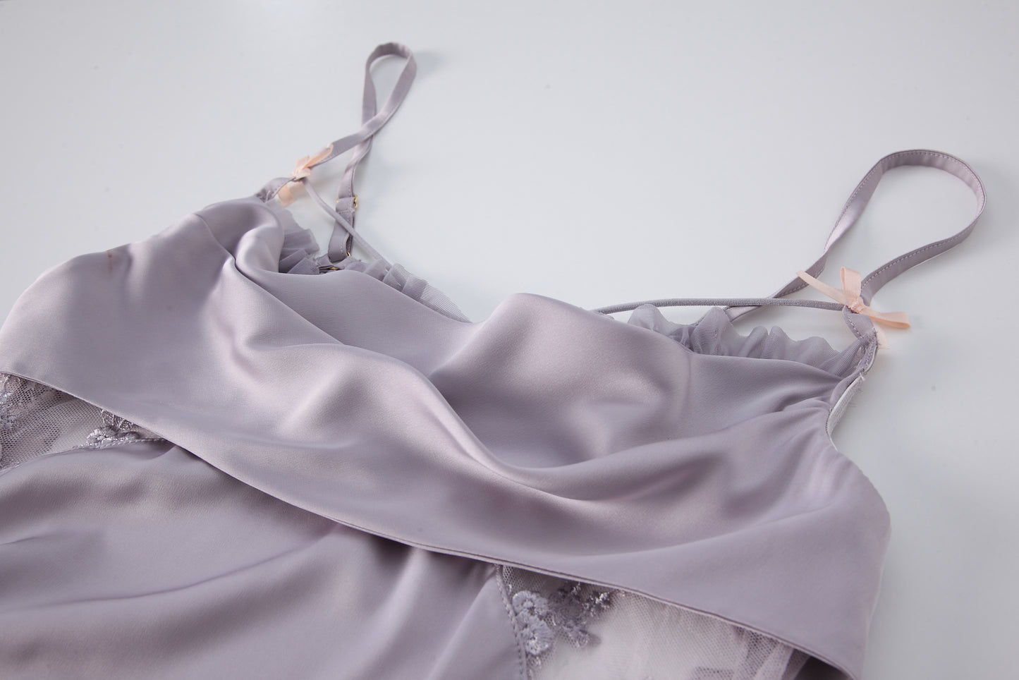 Close-up of a light purple silk nightgown with delicate lace trim and ribbon straps, showcasing the luxurious fabric and intricate details.