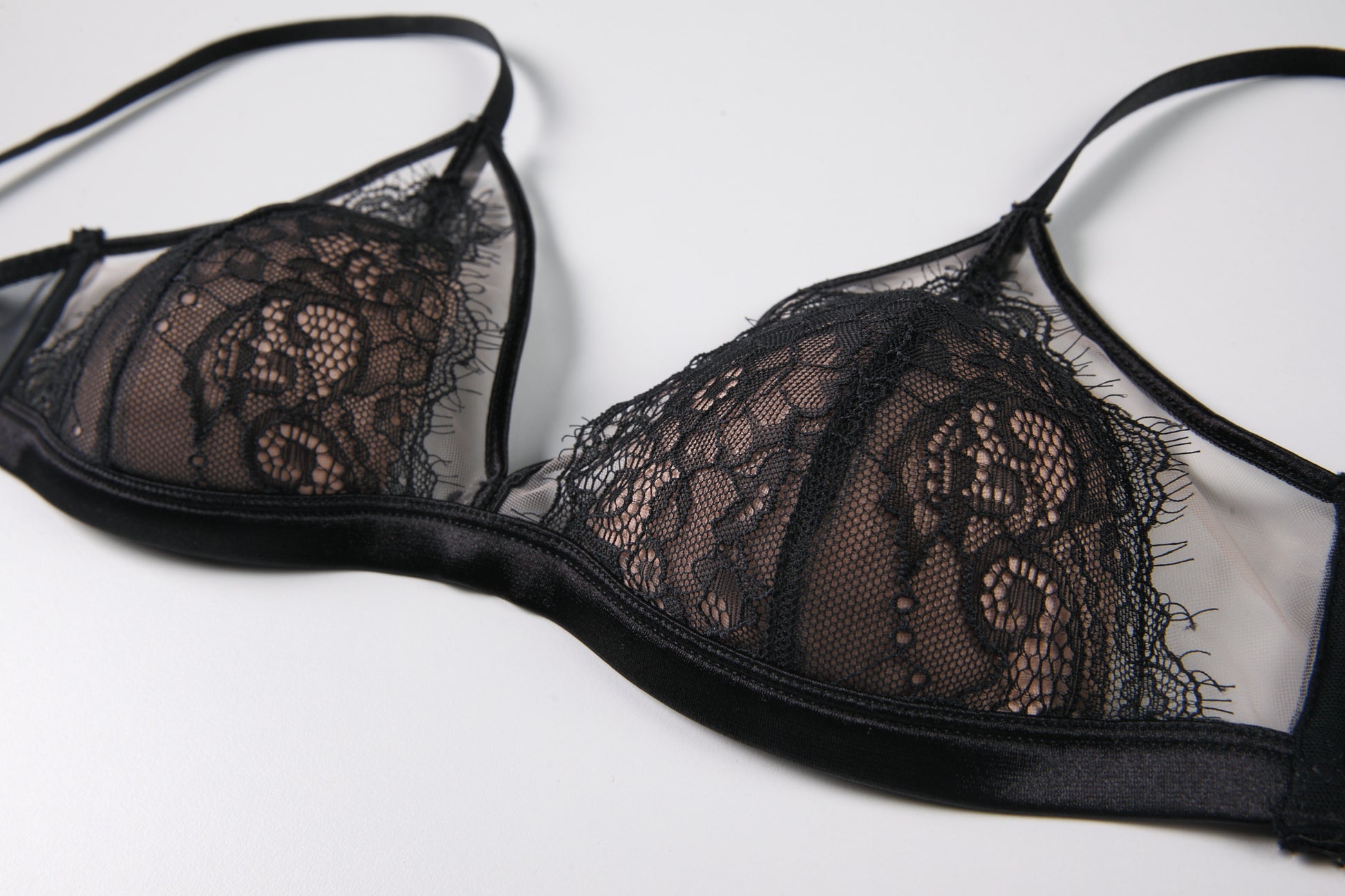Close-up of an elegant black lace bralette with a sheer floral design, featuring intricate lace details and soft, adjustable straps.