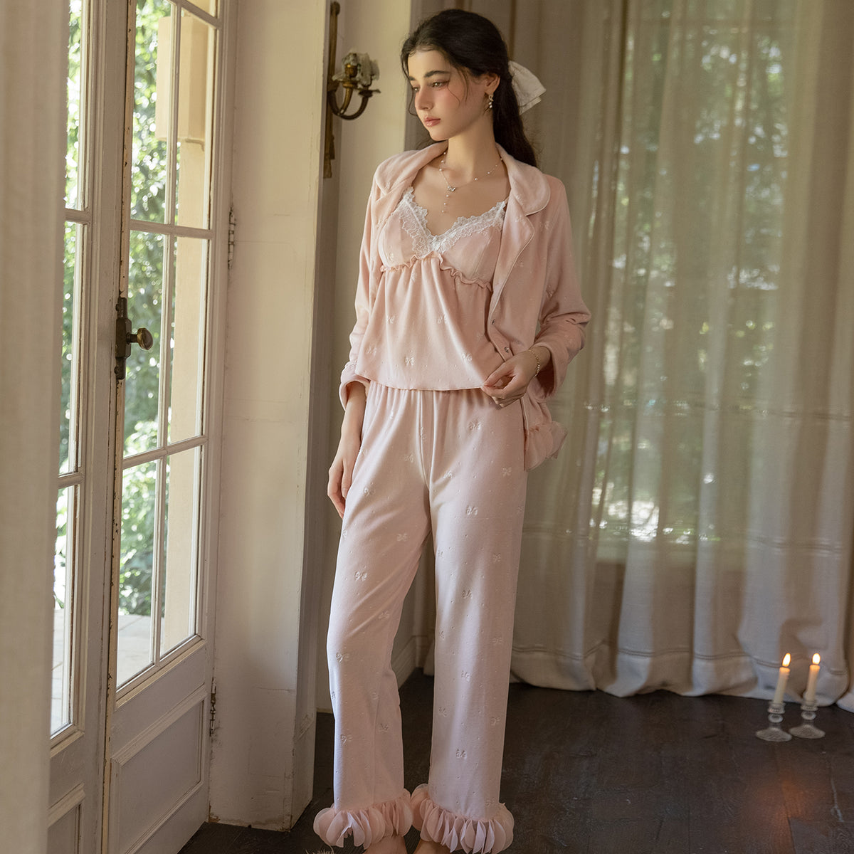 Model by a window wearing the blush pink cami, ruffle pants and matching cardigan