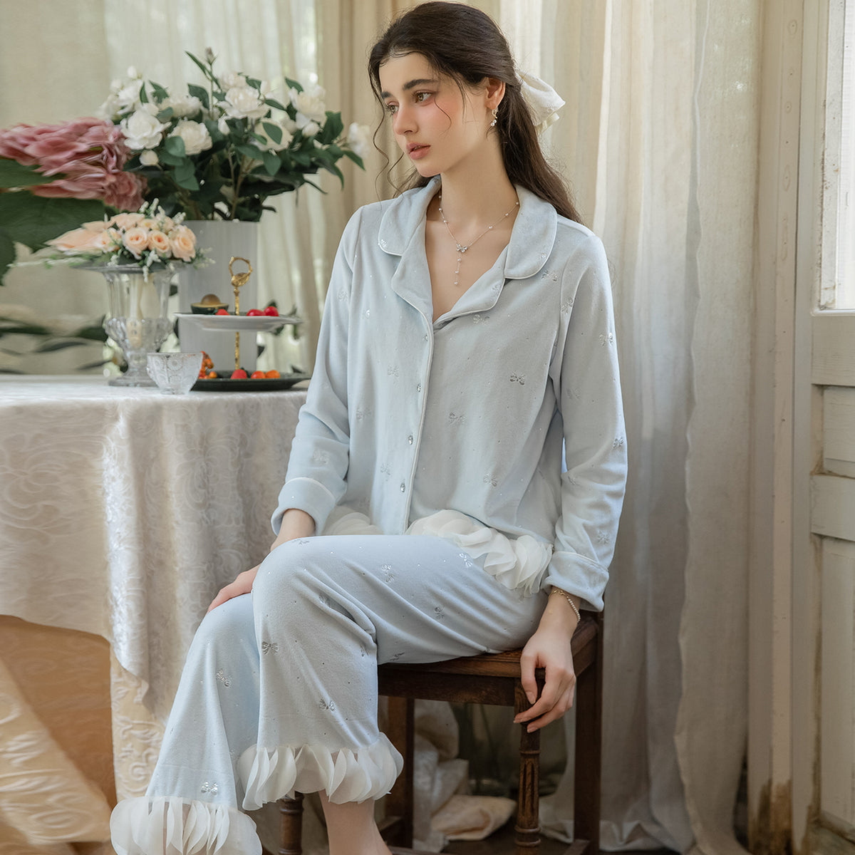 Seated model wearing the light blue button cardigan and matching ruffle-hem pants