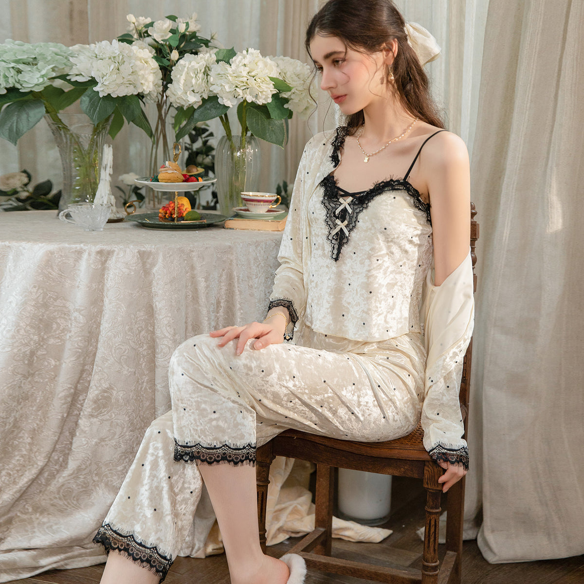 Seated model in the light yellow camisole and pants with the matching cardigan draped off the shoulders